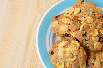 Group of cereal cookies in blue plate on wooden table. Freshly baked oats biscuits.