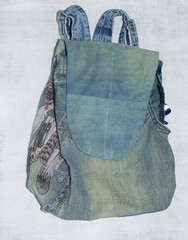 New things made from old jeans: backpack for kid from upcycling denim. Concept of things reuse and natural resources preserving.