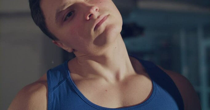 A close-up of man makes stretching the neck and tilting the head in the gym