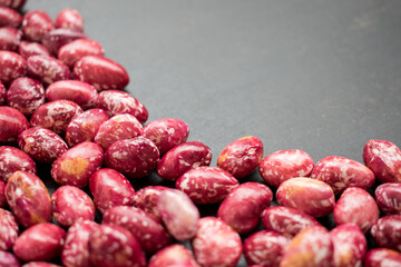Close up of some raw red beans on a black table 