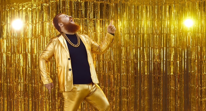 Side View Of Funny Crazy Uninhibited Chubby Young Man In Golden Suit Singing Songs And Having Fun At Disco Club Or Karaoke Party. Website Banner With Shiny Gold Background And Free Space For Text