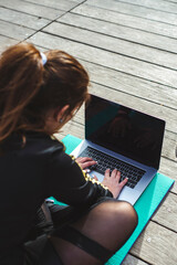 Fitness lifestyle. Girl is watching at a laptop video fitness lesson. Top view
