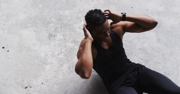 African american man doing crunches on the floor in an empty urban building