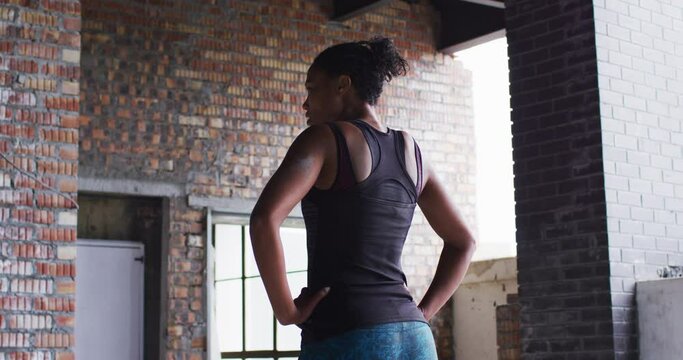 African american woman standing and resting after exercise in an empty urban building