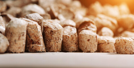A bunch of wood pellets for heating industrial boilers with solid fuel boilers on table. Background macro image of biomass pellets close-up. Eco-friendly and low cost fuel concept