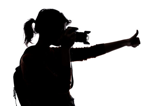 Silhouette of a photographer with a camera on a white background isolated for composites. She is posed with a thumbs up gesture