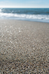 Fototapeta na wymiar Close up of sand grains on a beach with blurred coastline and horizon in background