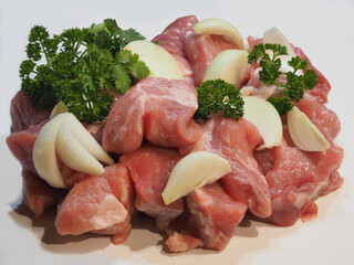 Fresh raw meat cut into pieces with onions and spicy herbs on a white background, closeup. Prepared natural pork meat for cooking shish kebab, minced meat