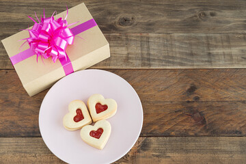 Dish with three heart-shaped cookies on a wooden base. Concept Valentine's Day, Mother's Day, anniversary and decorations. Copy space