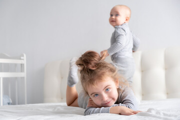 Obraz na płótnie Canvas baby boy and little girl sister having fun at home on bed. Home activities for kids.