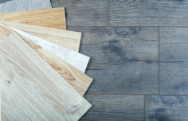 Vinyl and linoleum samples on a wooden background. Vinyl for flooring with wood grain texture and...