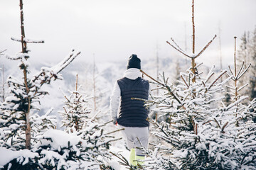 Sportliche, wandernde Person inmitten wunderschöner verschneiter Berg- und Waldlandschaft in...