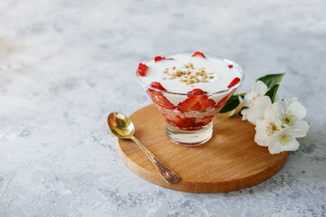 Healthy breakfast of strawberry parfait with fresh fruit and yogurt on a gray table.Oatmeal dessert...