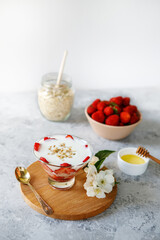 Fototapeta na wymiar Oatmeal dessert with fresh strawberries. Healthy breakfast of strawberry parfait with fresh fruit and yogurt on a gray table. Panna Cotta. Correct, natural nutrition. Space for text. Still life