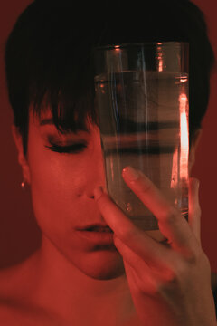 Portrait of a woman with her eyes closed holding a glass of water in studio