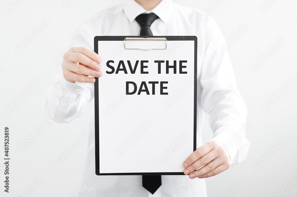 Poster save the date text on a white tablet in the hands of a businessman on a gray background.