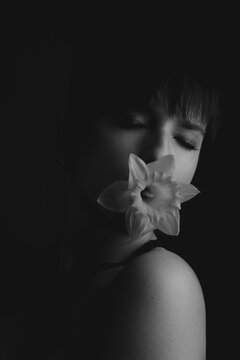 Black and white low key portrait of a woman with a flower in her mouth