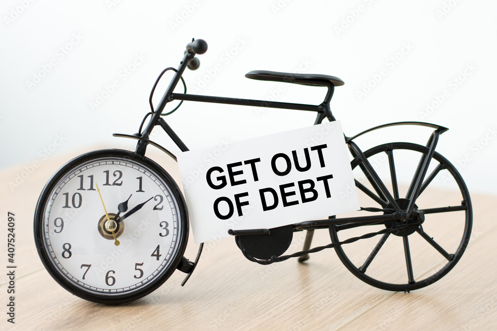 Poster text get out of debt on the business card next to the hour on the isolated table.