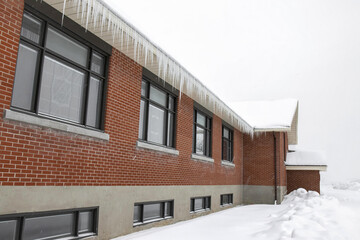Red brick building in snow with black metal clad windows, icicles nobody