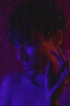 Portrait of a woman behind plastic bubble wrap with her eyes closed