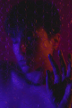 Portrait of a woman behind plastic bubble wrap with her eyes closed