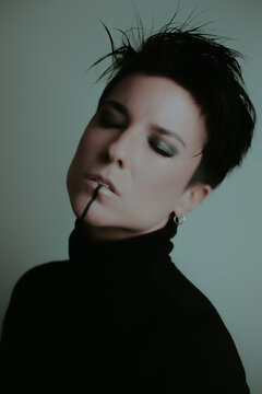Portrait of an attractive woman with her eyes closed and dark makeup in studio