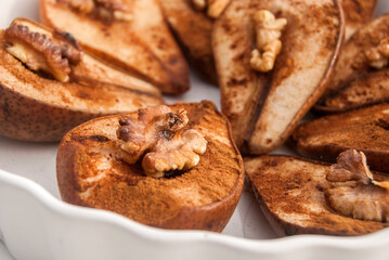 Baked pears with cinnamon powder and walnut core closeup as food background