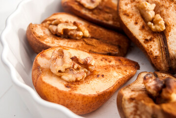 Baked pears with cinnamon powder and walnut core closeup as food background