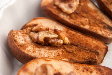 Baked pears with cinnamon powder and walnut core closeup as food background