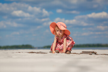 A little girl in a beautiful sarafna plays in the sand on the beach