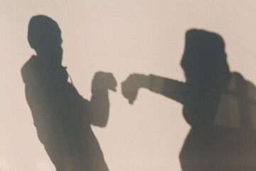 Fist hand in glove bumping safety greeting of two people shadow on wall of coronavirus COVID-19. New normal.