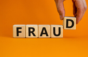 Fraud symbol. Concept word fraud on wooden cubes on a beautiful orange table. Businessman hand....