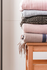 Obraz na płótnie Canvas Neatly folded casual sweaters lies on wooden chair