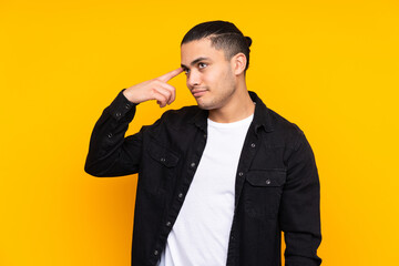 Asian handsome man isolated on yellow background surprised and pointing front