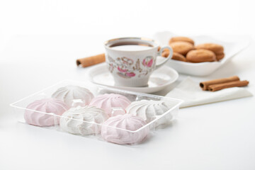 cup of hot tea marshmallow cookies cinnamon selective focus on white background high key