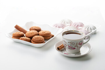 cup of hot tea marshmallow cookies cinnamon selective focus on white background high key