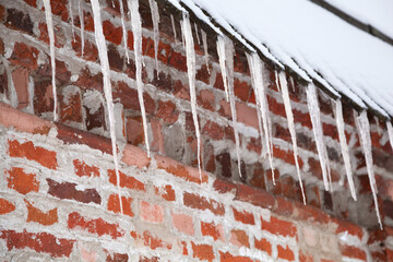 Icicles hang from the roof of the building close-up - 407529403