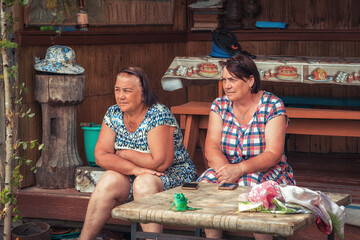 Couple senior women retirement age resting together on bench and looking into the distance in countryside in summer day