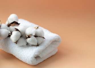 white, terry towel on a yellow background with a branch of cotton, close-up