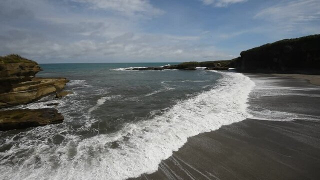 Waves breaking and surging up the beach at the end of the Truman Track, Punakaiki, New Zealand.