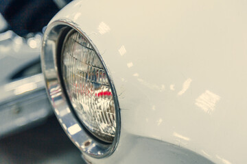 close-up halogen headlight of white retro car. car in the garage