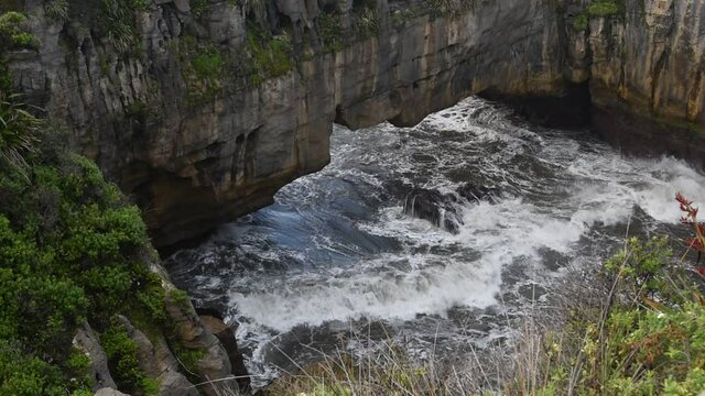 Surge pool at Pancake Rocks with the sea rolling in under a natural arch. Punakaiki, Paparoa National Park, New Zealand. 