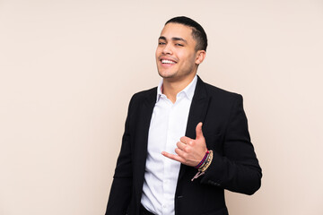 Asian business man isolated on beige background making phone gesture