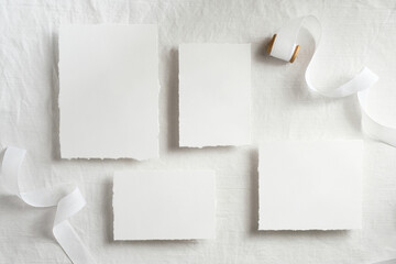 Wedding stationery set. Blank paper cards and white ribbon on textile background. Top view, flat...