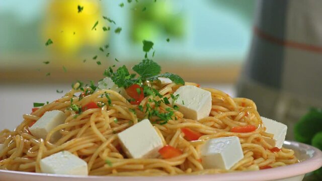 In slow motion, spaghetti pasta with tomato sauce cheese is thrown parsley. Slow motion video.