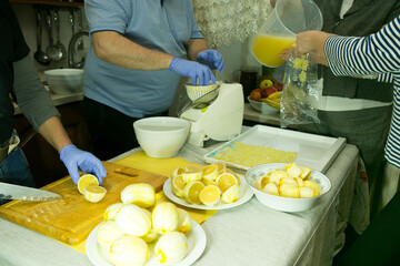 The process of making limoncello lemon liqueur at home. Four people work in the kitchen. Two men...