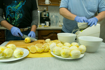 The process of making limoncello lemon liqueur at home. Two men are working in the kitchen. One of...