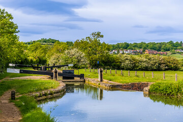 Fototapeta na wymiar A view past a flight of lock gates on the Oxford Canal towards the village of Napton, Warwickshire in summertime