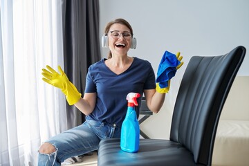 Woman doing house cleaning, female in headphones and gloves with detergent