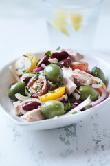 Salad with tuna, green olives and cherry tomatoes. Bright wooden background. Close up.